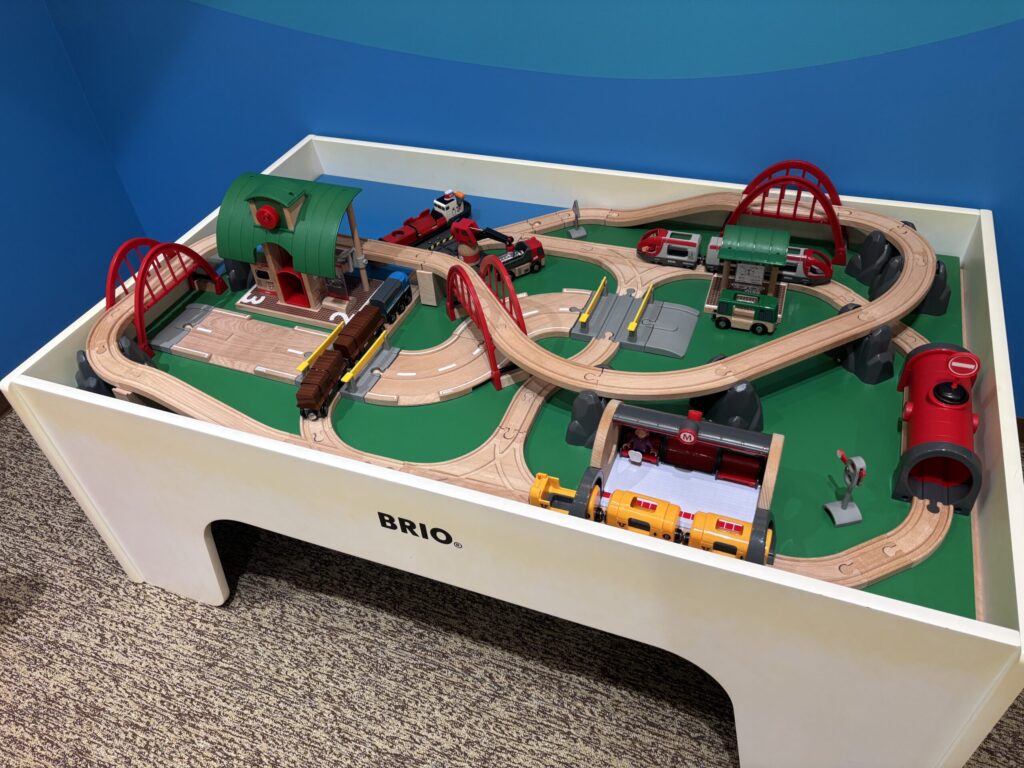 キッズパークの電車のおもちゃBRIOが机いっぱいに線路やバス停、お店など町が作られていた